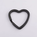Vista macro di un elegante anello portachiavi in metallo nero a forma di cuore su fondo grigio - Nero