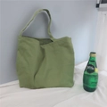 Detail of green canvas tote bag with long shoulder strap in a minimalist indoor setting - Bean Green