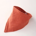 Macro shot of double-layer muslin cotton baby bib showing textured gauze and snap buttons - Brick Red