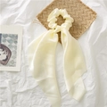 Close-up of cream satin scrunchie with long ribbons on a decorative background - Beige