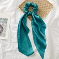 Teal satin scrunchie with long ribbons on a decorative woven mat and white background - Lake Blue