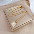 Detail of square gold necklace with heart shell pendant on luxury gift box packaging - Gold