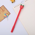 Stylo de Noël rouge avec embout en forme de fraise posé sur un carnet de notes - Cadeau de Noël