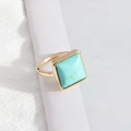 Minimalist square turquoise ring with golden finish on a clean white fabric surface - Large Size Turquoise