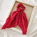 Detail van rode polka dot scrunchie met lang lint op een rustieke houten lijst - Rode Polka Dot