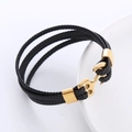 Dettaglio di bracciale in pelle multistrato con chiusura ad ancora dorata su piatto - Oro