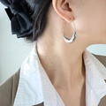 Pendientes largos de acero inoxidable con textura irregular usados por una modelo - Oro de 18K / Color Acero