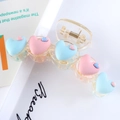 Detail of transparent acrylic hair claw featuring colorful matte resin heart decorations - Blue + Pink Hearts