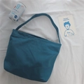 Detail shot of cyan canvas shoulder bag on white fabric with decorative props - Denim Blue