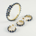 Dettaglio set di gioielli dorati con pietre preziose quadrate blu su bracciale e orecchini - Zirconia Blu