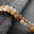Pulsera artesanal con cuentas redondas de calcedonia natural en tonos ámbar y gris - Jade de Seda Dorada
