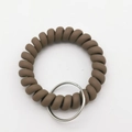 Close-up of matte dark brown spiral telephone wire wristband with silver metal keyring - Khaki