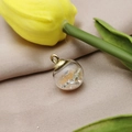 Macro shot of glass ball pendant filled with orange beads and crystals on beige fabric - Champagne
