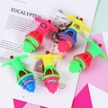 Five colorful plastic glowing gyro toys in pink, blue, green, and yellow displayed on a magazine - Glow Spinning Top