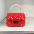 Detail of red PVC mini jelly bag with pearl handle and quilted texture for kids - Red