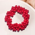 Macro shot of elegant red faux pearl beaded hair tie on a white ceramic plate tray - Red