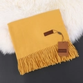 Yellow cashmere feel scarf with fringe tassel and brand tag on soft plush background - Bright yellow