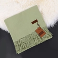 Soft green cashmere scarf with fringe details and woven brand label on white fur background - Avocado Green
