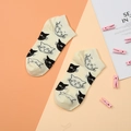 Nahaufnahme von cremefarbenen Baumwollsocken mit niedlichen schwarzen und weißen Katzenmustern - Weiß - Schwarz-Weiße Katze