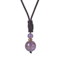 Detailed macro view of amethyst pendant with gold accents on black braided cord necklace - Amethyst Style