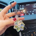 Porte-clés fleur en cristal scintillant avec anneau argenté dans un décor de voiture - Blanc
