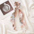 Detail view of pink floral hair scrunchie with long ribbons on a minimalist fabric background - Triangle Streamer / Pink