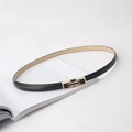 Fine ceinture noire en similicuir avec boucle rectangulaire dorée posée sur un livre élégant - Noir