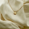 Elegante collar con colgante de corazón dorado pulido y cadena minimalista sobre seda - Dorado