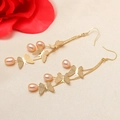 Elegant butterfly drop earrings with pink pearls and gold-plated finish on a soft fabric background - Pink