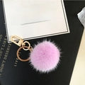 Plush purple mink fur pompom keychain with golden metal clasp on a textured background - Pink Purple