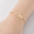 Pulsera dorada de acero inoxidable con colgante de montaña hueco en una muñeca - Dorado