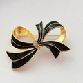 Détail d'une broche nœud vintage avec émail noir, bordure dorée et strass brillants - Style Nœud Noir (C)