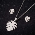 Conjunto de joyas con collar y pendientes de hoja de monstera sobre fondo brillante - Juego De Collar Y Pendientes / Color Acero