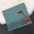 Teal Morandi solid cashmere scarf with tassel edges on a white faux fur rug - Peacock Blue