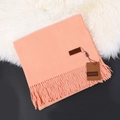 Pink cashmere winter scarf with elegant tassels folded on a soft faux fur background - Sunny Orange