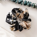 Detail view of smooth satin scrunchie with elegant beige floral pattern on black fabric - Flower Black
