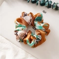 Brown satin scrunchie with white and green floral patterns on a minimal background - Floral Orange