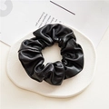 Detail view of a black PU leather scrunchie placed on a white decorative tray - Leather Black