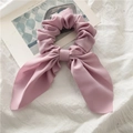 Detailopname van roze scrunchie met strik die de fijne stoftextuur laat zien - Roze