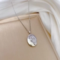 Détail d'un collier en acier titane argenté avec un pendentif ovale en relief de rose - Acier titane / Argenté