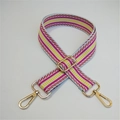 Macro shot of light blue woven bag strap with colorful geometric patterns and gold metal buckles - Pink