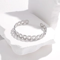 Detail shot of silver geometric lattice cutout bangle on white stone with side lighting - Steel