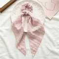 Detail of pink lace ribbon scrunchie with wavy texture on a decorative white plate - Style with Streamer / Pink