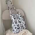 Detail of canvas tote bag featuring black butterfly prints and branded woven label - Butterfly