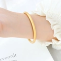 Minimalist 18K gold plated matte titanium steel bangle worn with elegant white sleeves - Gold