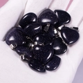 Blue goldstone heart-shaped pendants with silver bails held in a gloved hand - Blue Sandstone