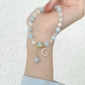 Detalle de pulsera de cuentas con piedras azul mar y colgantes de luna dorada - Luna
