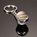 Macro shot of Jupiter pattern glass dome keychain with metal ring on reflective surface - Jupiter