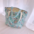 Close-up of small floral tote bag with blue patterns, canvas texture and metal zipper - Light Blue With Orange Pink Flowers