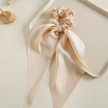 Close-up of champagne satin scrunchie with long ribbons on a minimalist tray - Beige